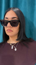 Inquadratura frontale ravvicinata degli Occhiali Maira neri lucidi, evidenziando la montatura bold squadrata con punte allungate stile cat-eye.