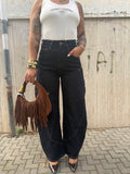 Jeans Ballons a palloncino in denim blu scuro a vita alta con cuciture geometriche a contrasto FAEV, abbinato a canotta bianca e borsa con frange.