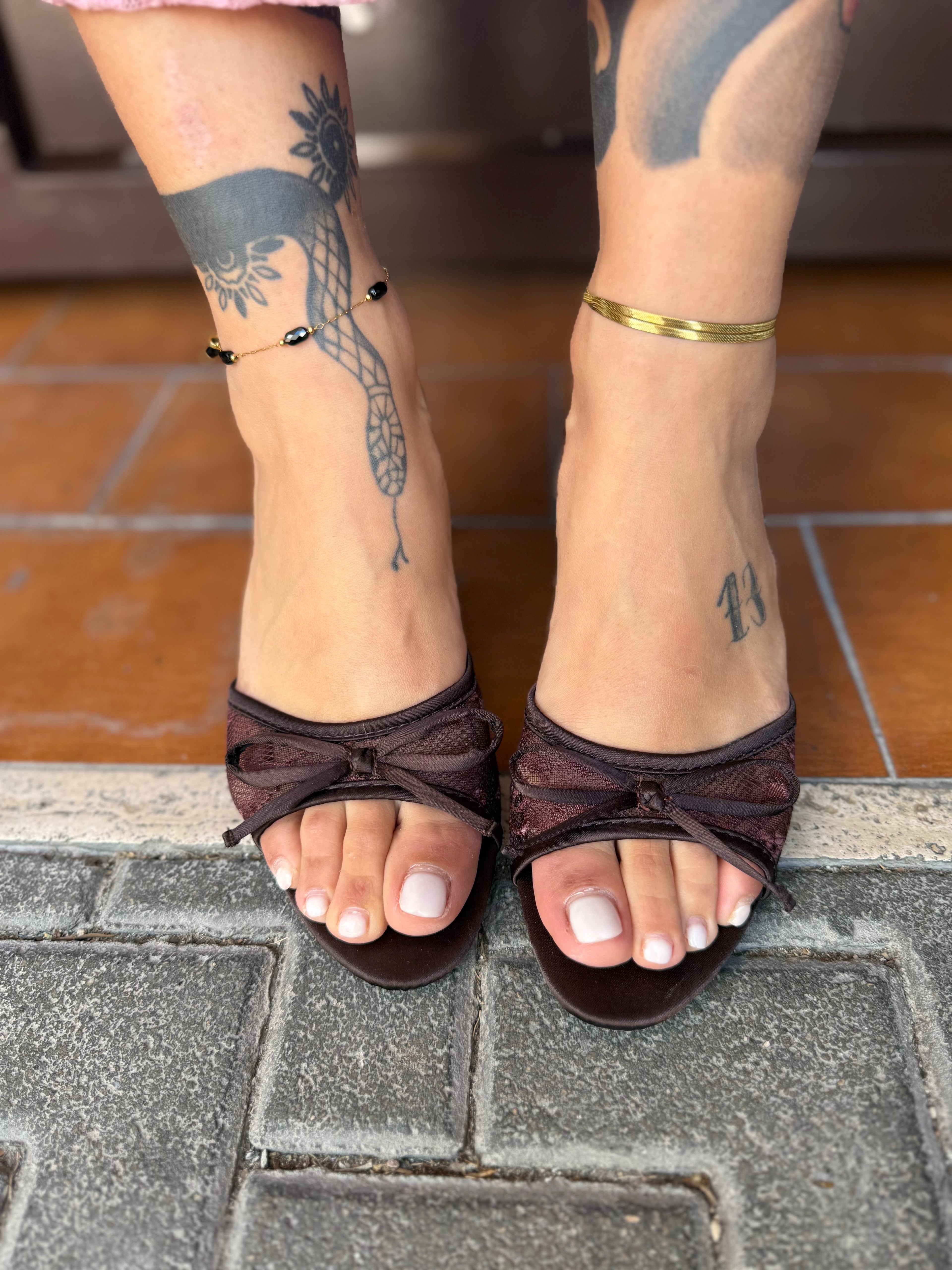 Dettaglio frontale della ciabattina bordeaux FAEV, che mostra la fascia in pizzo floreale, il profilo in satin lucido e il fiocchetto decorativo.