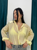 Camicia Positano gialla a righe verticali semitrasparente FAEV, indossata aperta con top giallo e shorts di jeans a vita alta.