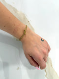 Dettaglio del Bracciale Nodo dorato indossato al polso, che mostra la sottile maglia intrecciata flessibile e il particolare del nodo d'amore al centro.