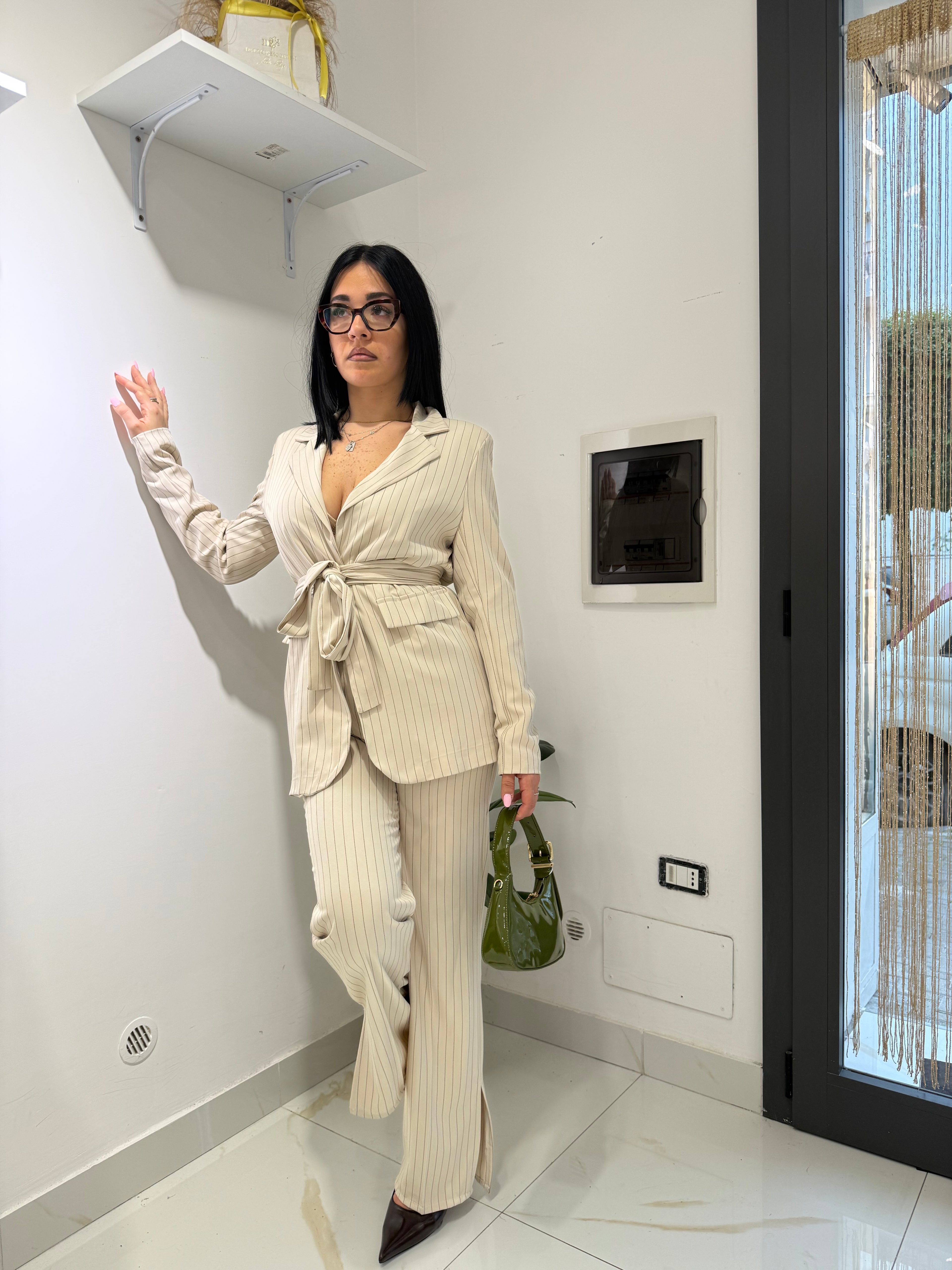 Inquadratura intera del completo Tailleur Amelie color panna gessato, che mostra la vestibilità fluida del pantalone e la giacca avvitata con fusciacca.