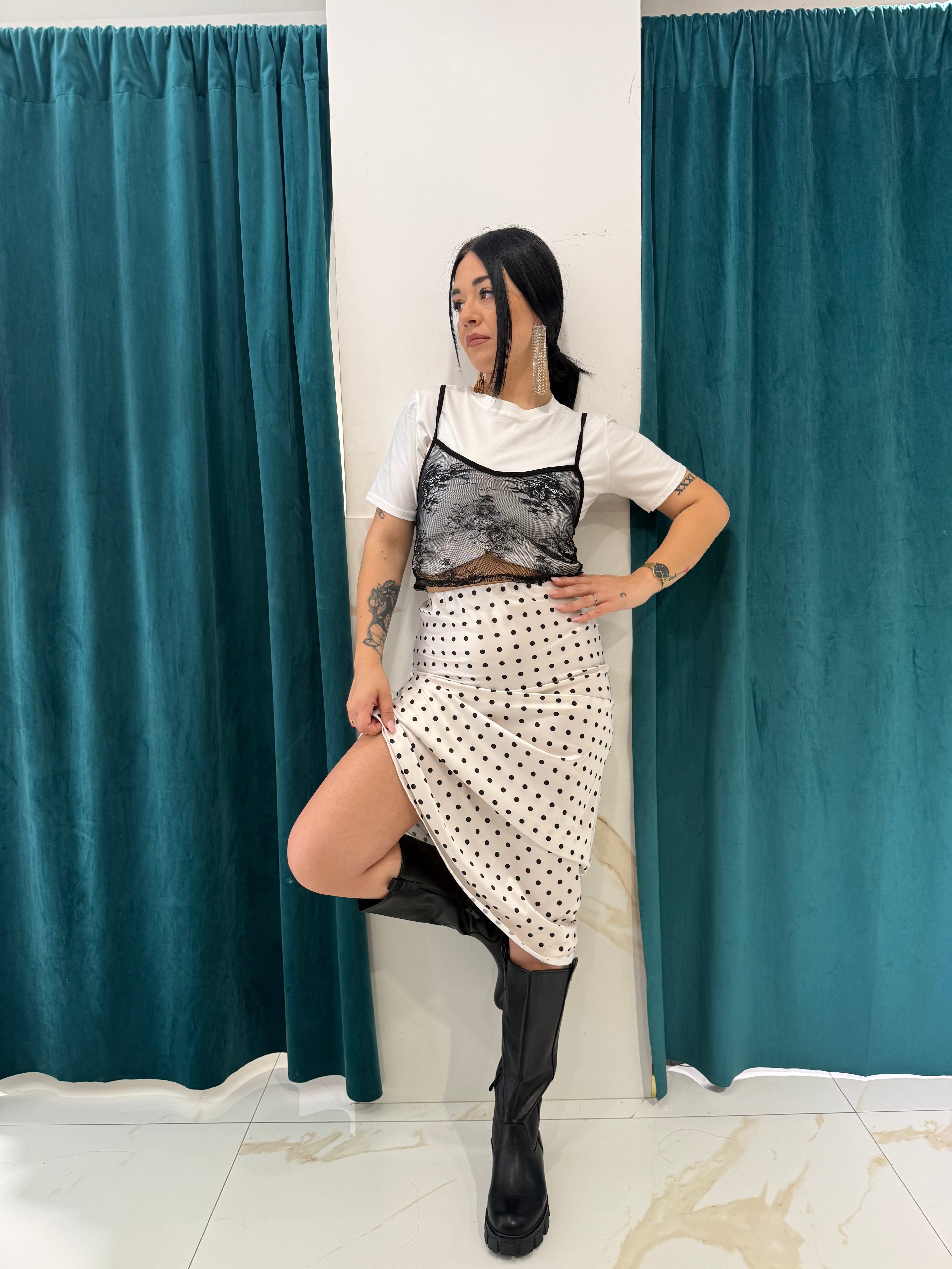 Gonna a pois bianchi e neri con spacco laterale FAEV, abbinata a t-shirt bianca con top in pizzo nero e stivali alti.