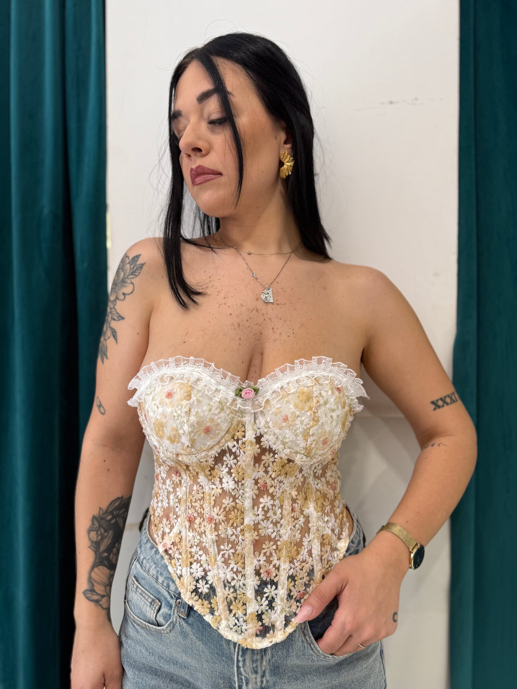 Corpetto Margherita a corsetto in pizzo ricamato a fiori gialli e rosa FAEV, indossato con jeans a vita alta.