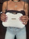 Handbag Coconuda a mano realizzata all'uncinetto bianco latte con manico intrecciato marrone cioccolato e logo dorato, tenuta in mano. FAEV