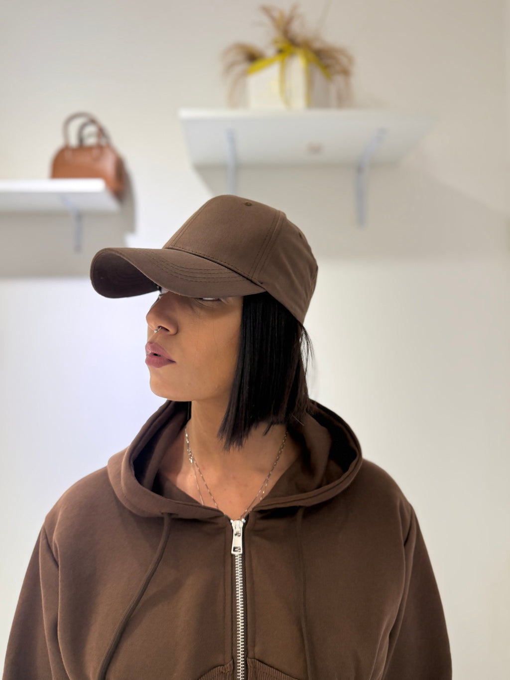 Cappello Karim berretto con visiera curva marrone cioccolato FAEV, indossato di profilo in abbinamento a una felpa marrone con zip.