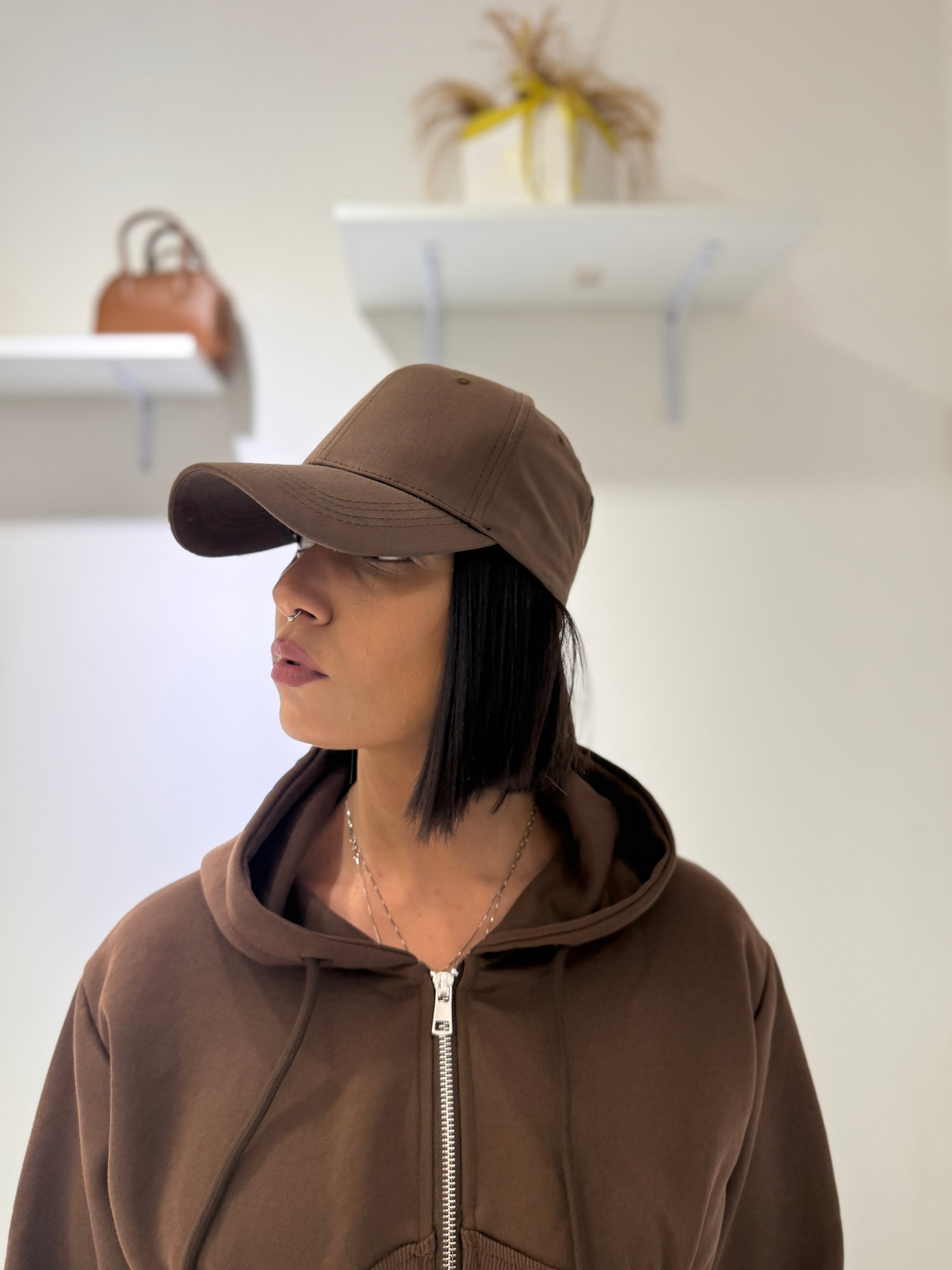 Cappello Karim berretto con visiera curva marrone cioccolato FAEV, indossato di profilo in abbinamento a una felpa marrone con zip.