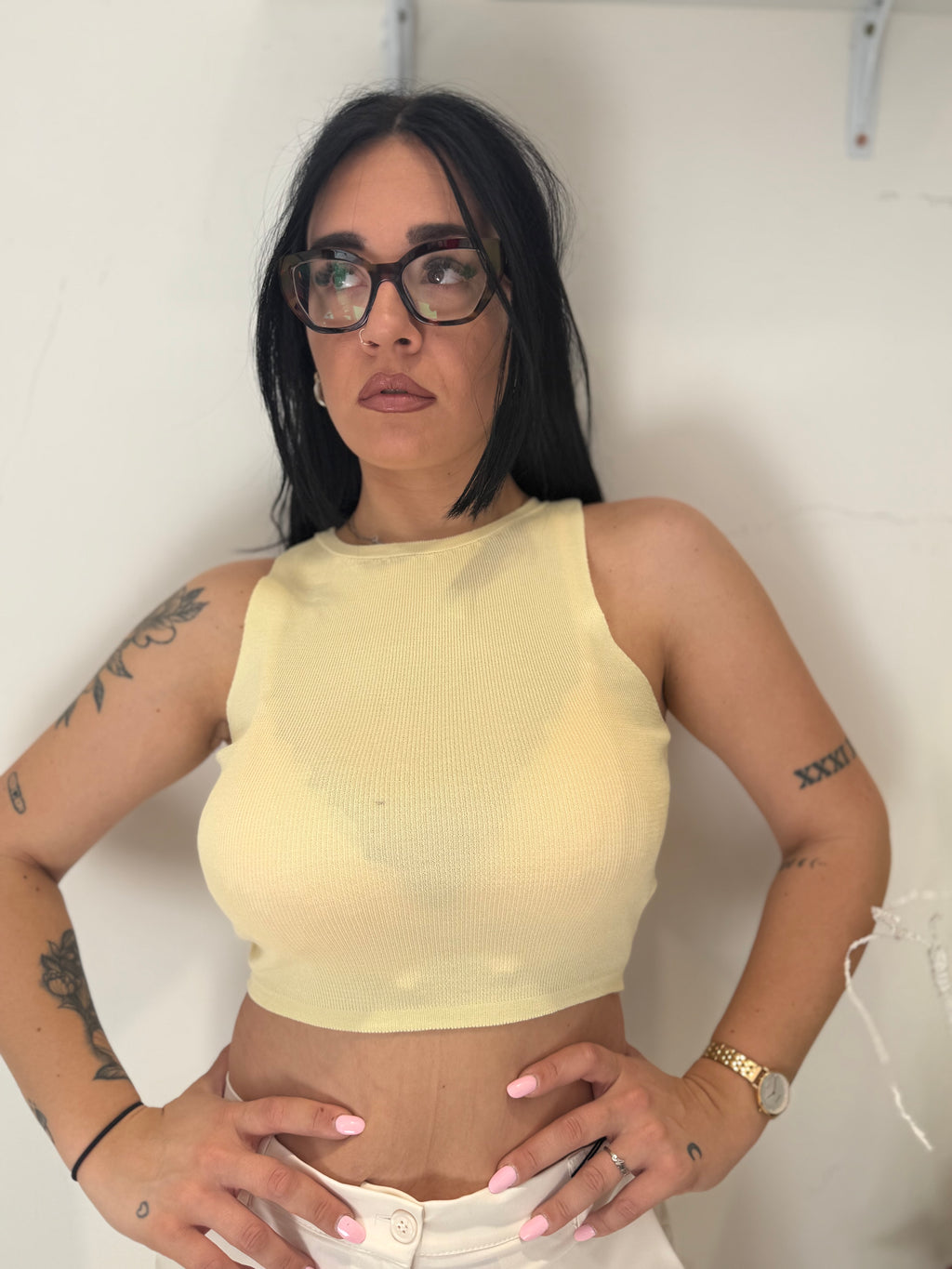 Top Penelope crop smanicato in maglia di filo leggero color giallo limone pastello, con scollatura rotonda a girocollo, abbinato a pantaloni bianchi. FAEV