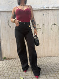 Jeans Leila a gamba larga in denim nero a vita alta FAEV, abbinato a body bordeaux con scollo a cuore e scarpe col tacco a punta.