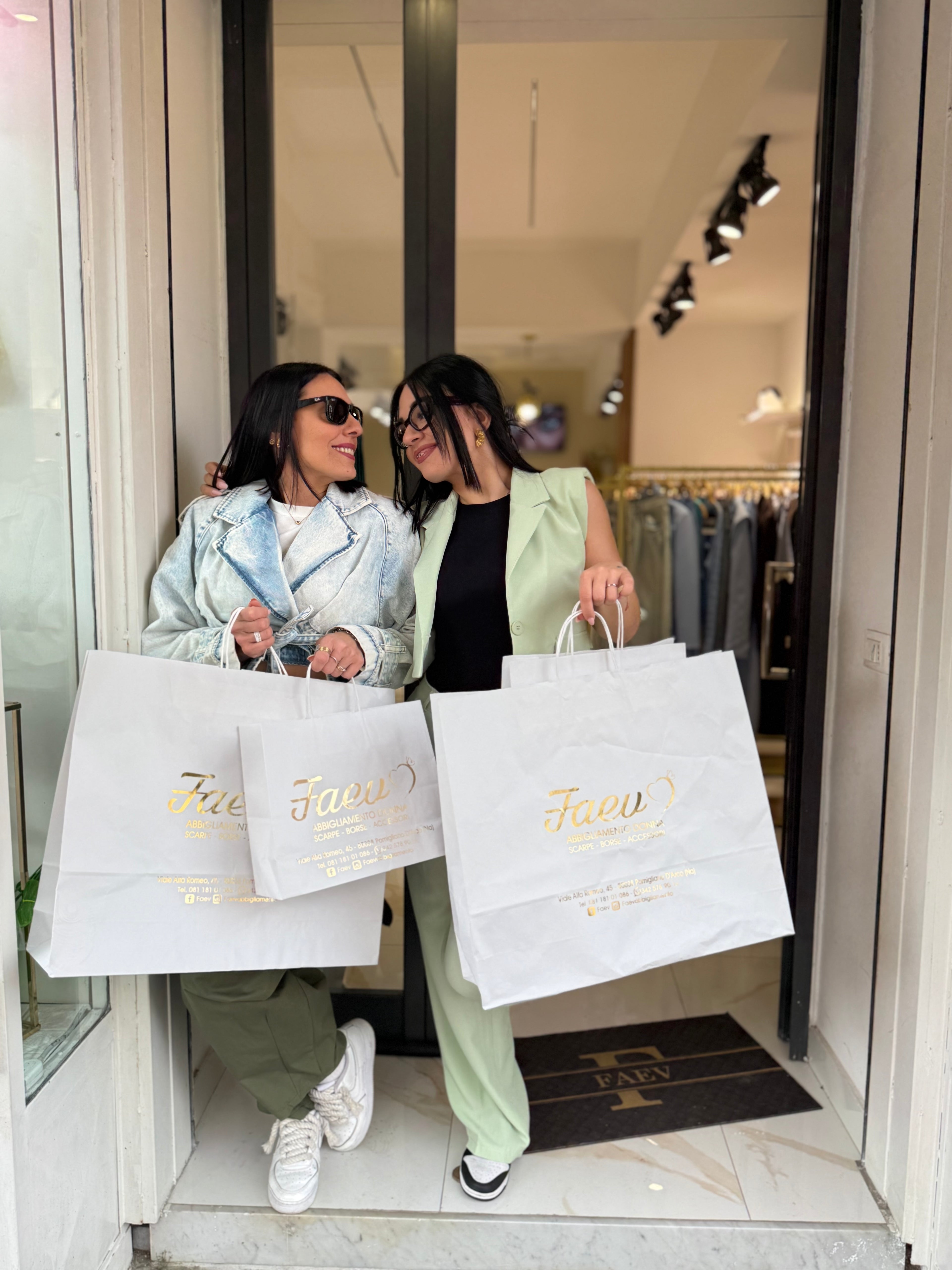 Ingresso dello store FAEV Abbigliamento Donna; proprietarie con shopping bag bianche logate e zerbino personalizzato FAEV.